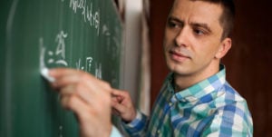 young man at chalkboard doing math problem