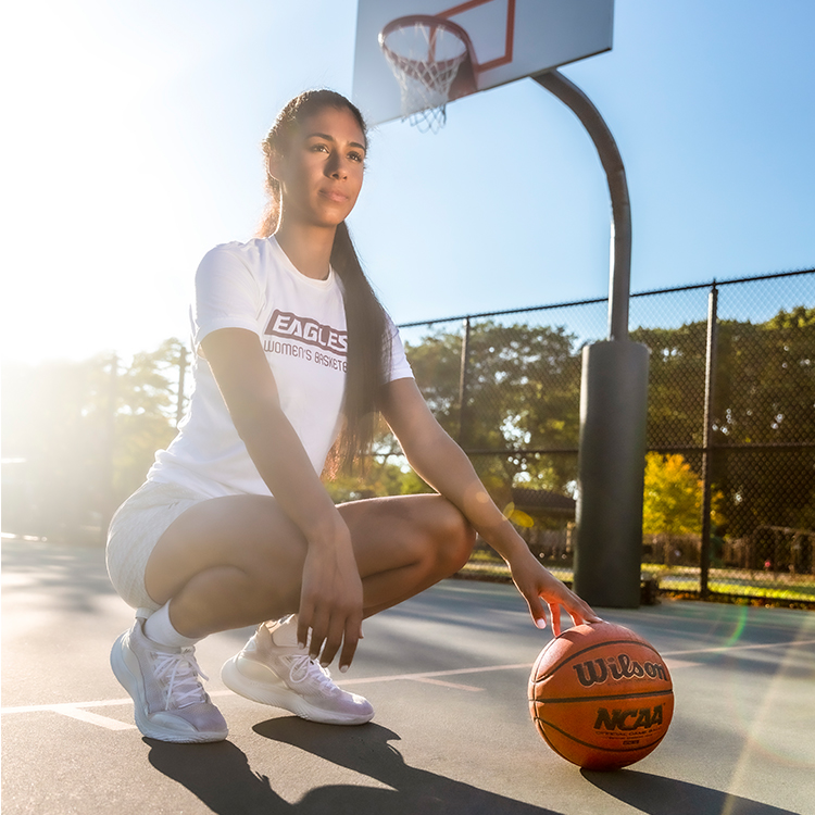 Tai Pagan crouching on a basketball court with her hand on a basketball