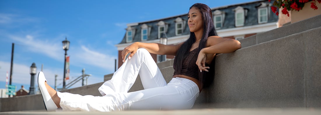 Tai Pagan sitting on the ground with her back resting on a short wall 